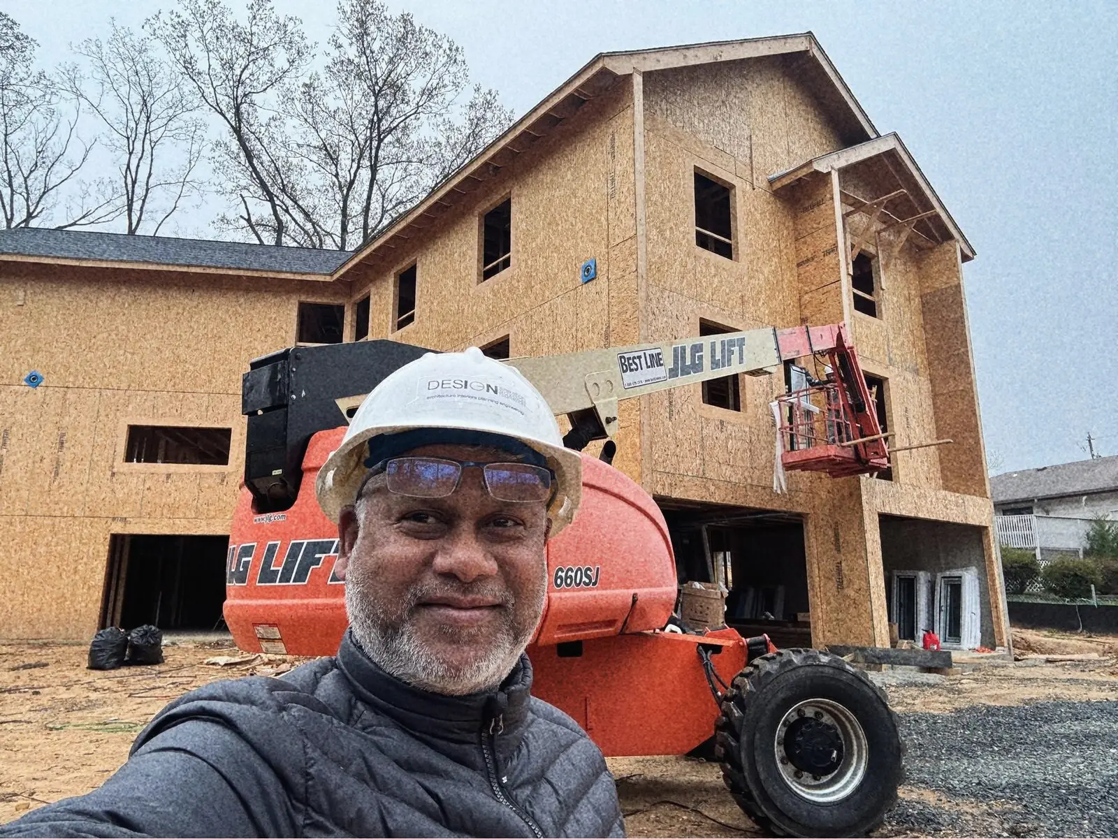 Moshfeq Rahman in a hard hat in front of a house under construction